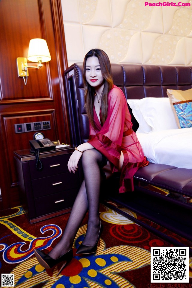 A woman sitting on a bed in a hotel room.