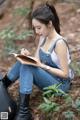 A woman sitting on the ground writing in a notebook.