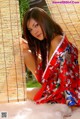 A woman in a red kimono sitting on a white fur rug.