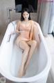 A woman sitting in a bathtub with her legs in the water.