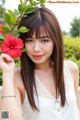 A woman holding a red flower in her hand.