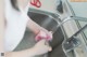 A woman is washing her hands in the kitchen sink.