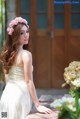 A woman in a white dress with a flower crown on her head.