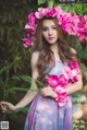 A woman in a blue dress holding a bunch of pink flowers.