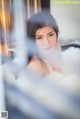 A woman sitting in a bathtub filled with foam.