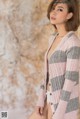 A woman in a pink and gray striped cardigan posing for a picture.