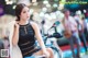 A woman in a black dress sitting on a motorcycle.