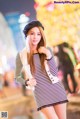 A woman in a striped dress and hat posing for a picture.