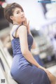 A woman in a blue dress sitting on an escalator.