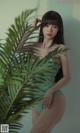 a woman in a green bathing suit posing next to a palm tree