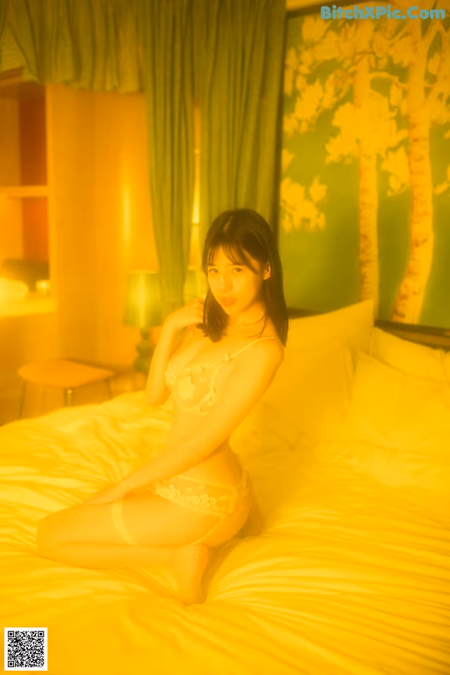 A woman sitting on a bed in a white lingerie.