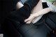 A woman in a black dress and high heels sitting in a car.