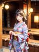 A woman in a kimono standing in front of a building.