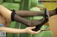 A woman in black stockings and high heels is sitting on a green chair.