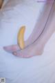 A banana sitting on top of a bed next to a woman's feet.