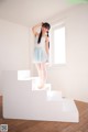 A woman in a blue dress standing on a white staircase.