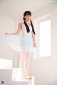 A young ballerina in a white leotard and blue tutu posing for a picture.