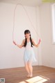 A young woman holding a skipping rope in a room.