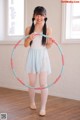 A young girl is holding a hula hoop in her hands.