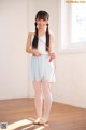 A young woman in a white dress holding a skipping rope.