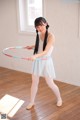 A young woman in a white dress holding a hula hoop.