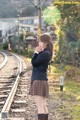 A woman in a school uniform standing on a train track.