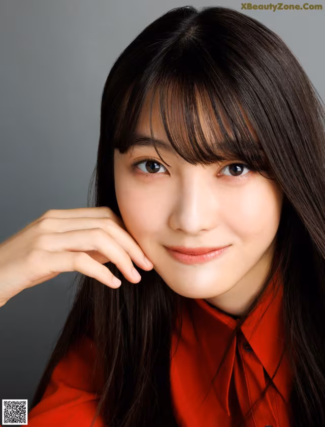 A woman with long black hair wearing a red shirt.