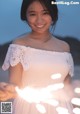 A woman in a white dress holding a string of lights.