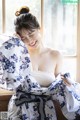 A woman in a blue and white floral robe sitting on a window sill.