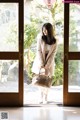 A woman standing in front of a glass door holding a handbag.