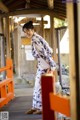 A woman in a kimono standing on a wooden walkway.