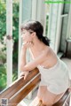 A woman in a white dress sitting on a wooden bench.