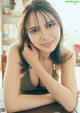 A woman sitting at a table with her hand on her chin.