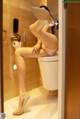 A woman sitting on top of a toilet in a bathroom.