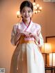 A woman in a pink and white hanbok is posing for a picture.