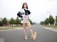 A woman standing in the middle of a street wearing a skirt and jacket.