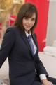 A woman in a business suit sitting on a bed.