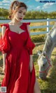 a woman in a red dress standing next to a white horse