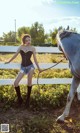 A woman standing next to a white horse in a field.