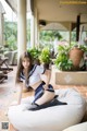 A woman in a school uniform sitting on a bean bag chair.